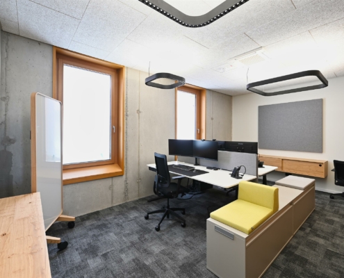 Arbeitsplätze von Schneider Enginering in Fulda mit modernen Büromöbeln und Sichbetonwand